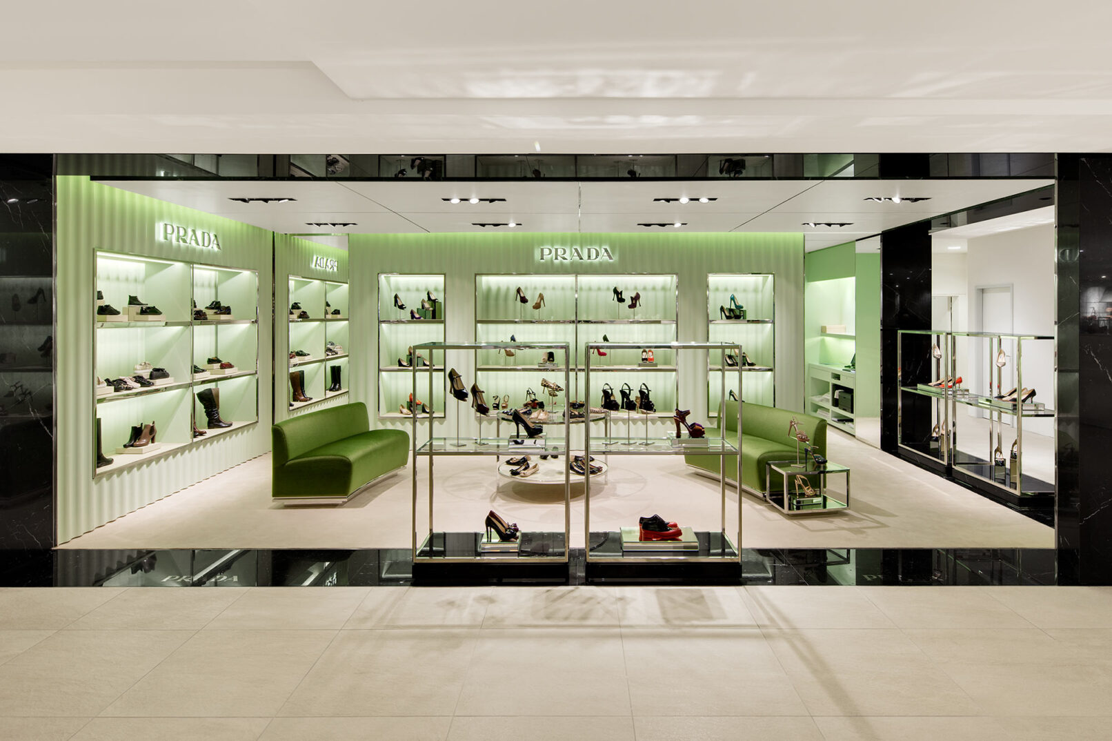 Verkaufsfläche der Marke Prada mit grünem gewelltem Schuhregal und edlen Damenschuhen bestückt.