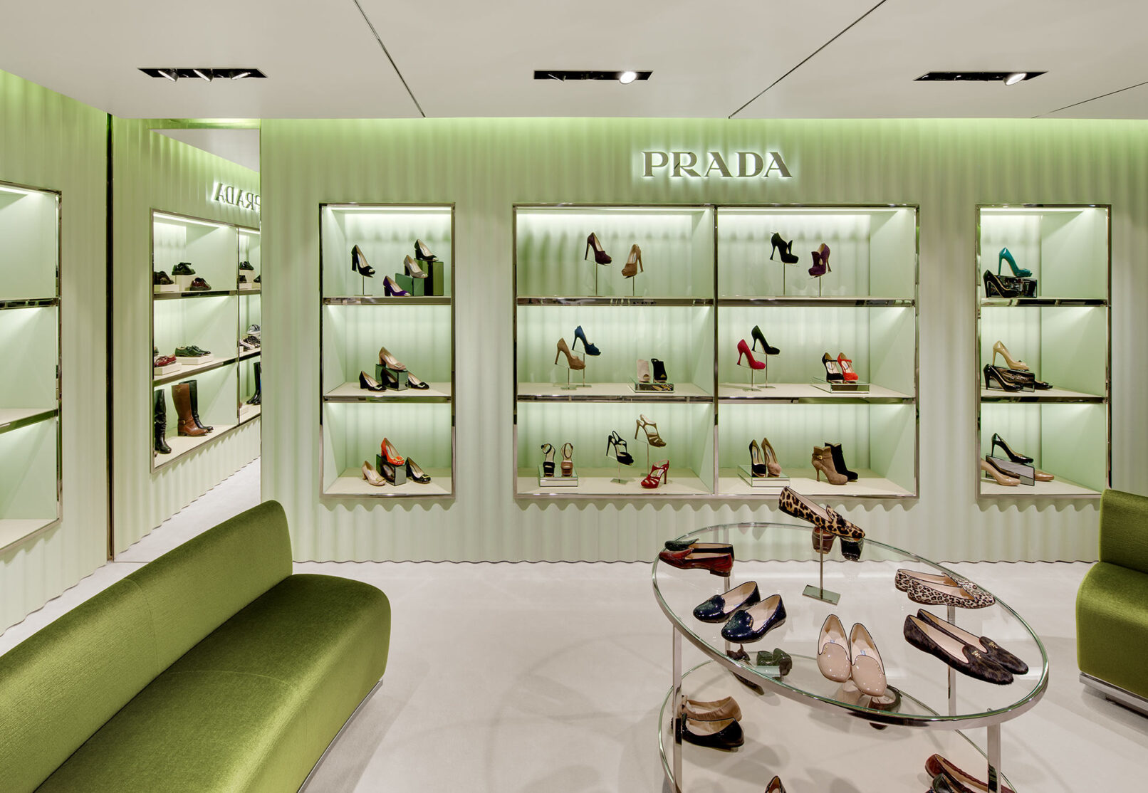 Grünes gewelltes Schuhregal der Marke Prada mit edlen Damenschuhen bestückt.
