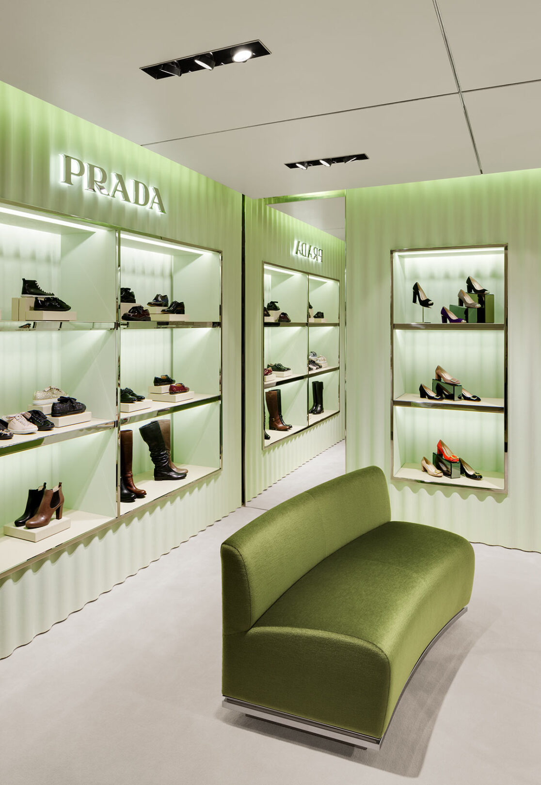 Grünes gewelltes Schuhregal der Marke Prada mit edlen Damenschuhen bestückt.