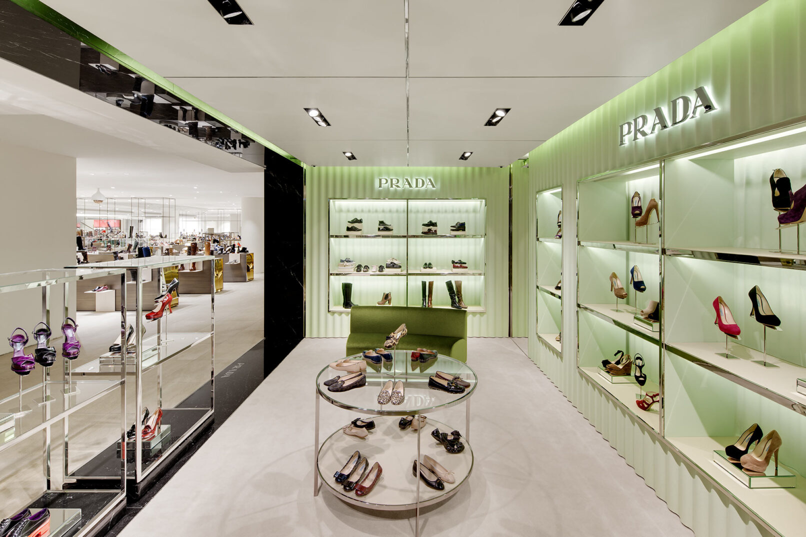 Grünes gewelltes Schuhregal der Marke Prada mit edlen Damenschuhen bestückt.
