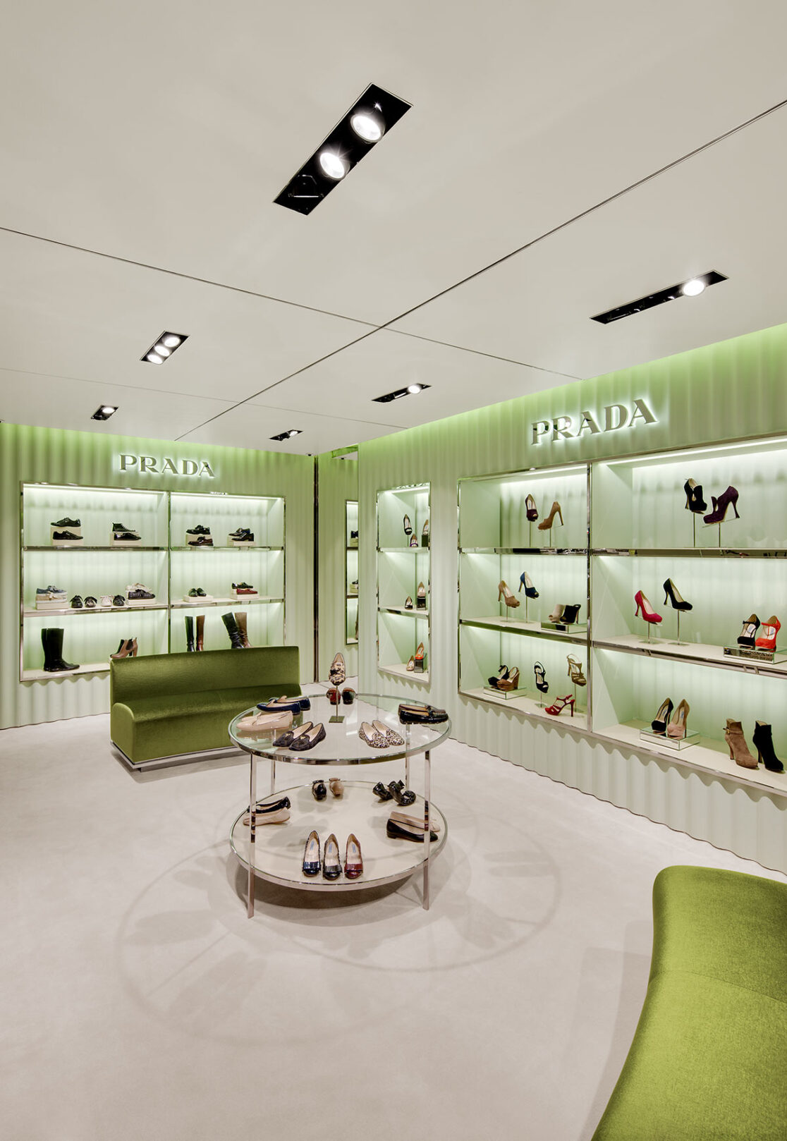 Grünes gewelltes Schuhregal der Marke Prada mit edlen Damenschuhen bestückt.