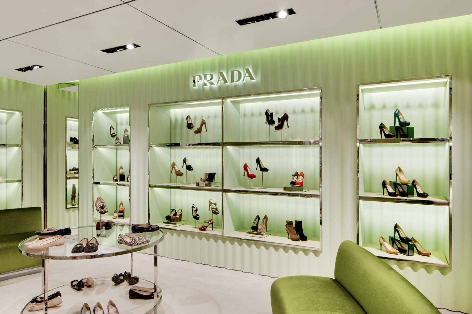 Grünes gewelltes Schuhregal der Marke Prada mit edlen Damenschuhen bestückt.